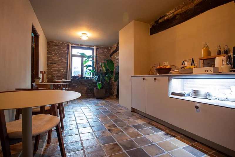 De ontbijtruimte met de oude bakstenen muur, de houten tafel en het buffet