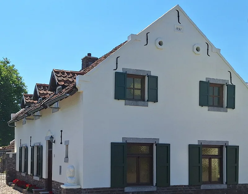 Het huis nu, vanuit dezelfde hoek: de witte puntgevel met groene luiken en het jaartal 1691 in de top
